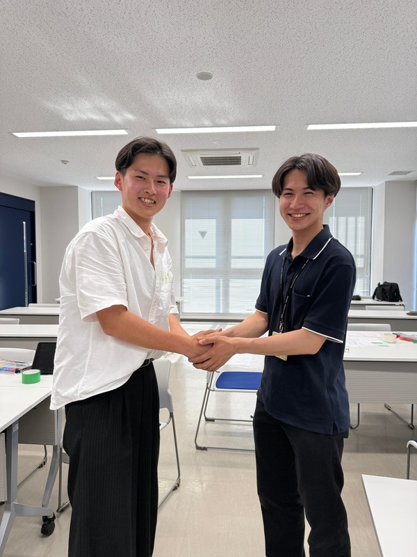 交流会会場で握手を交わす二人